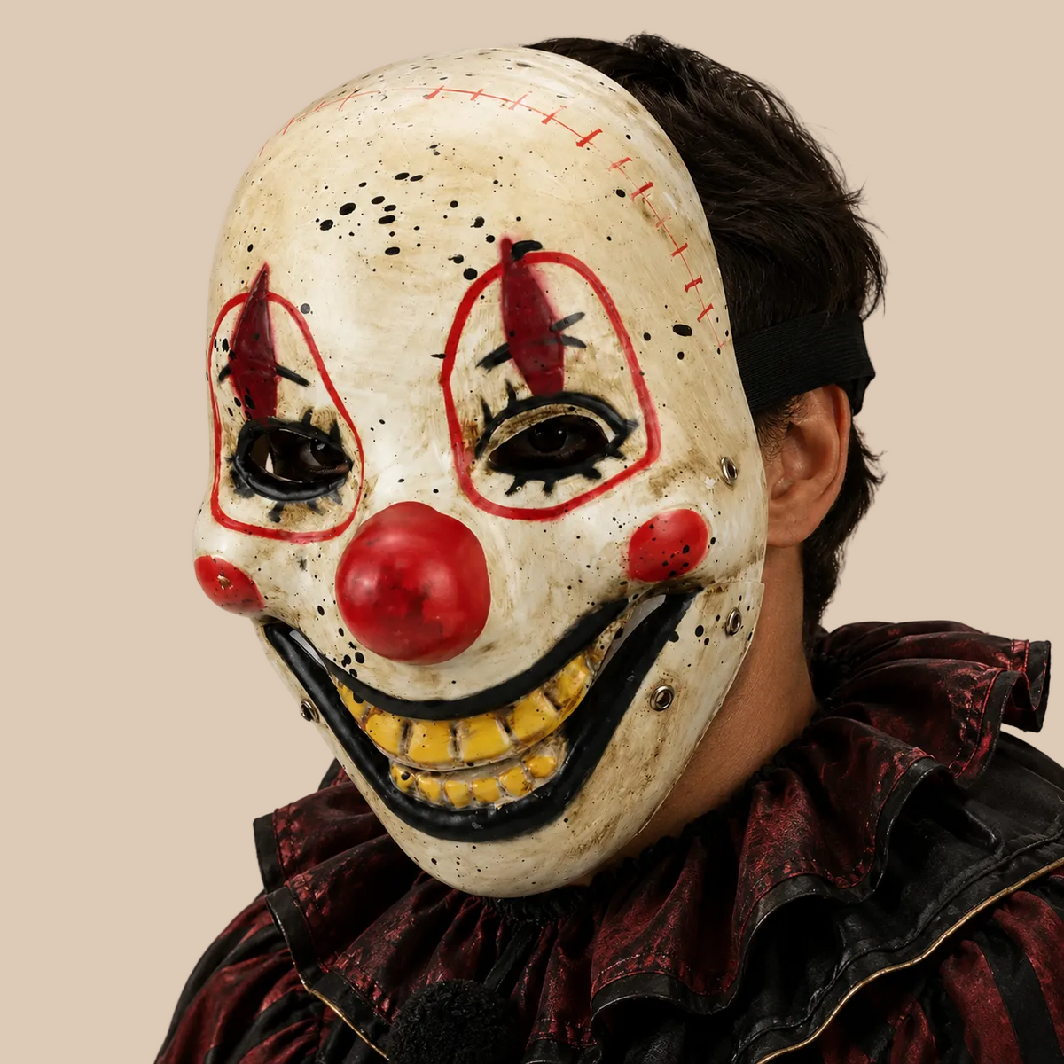 Clown mask with red nose and exaggerated grin, side view